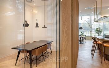 Moderne vergaderruimte met glazen wanden en stijlvolle houten accenten op Europalaan 40, Utrecht Zuid. Donker tafelblad, comfortabele stoelen, decoratieve lampen; ideaal voor kantoorruimtes of kantoren om te huren.
