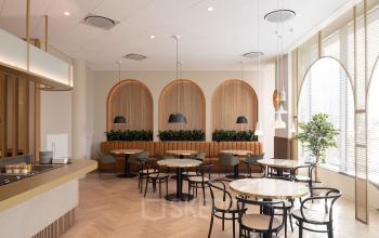 Interieur van een modern kantoorpand aan de Europalaan 40 in Utrecht Zuid met houten vloeren, ronde tafels, en stijlvolle verlichting. Ideale locatie voor kantoorruimte huren met een frisse uitstraling.