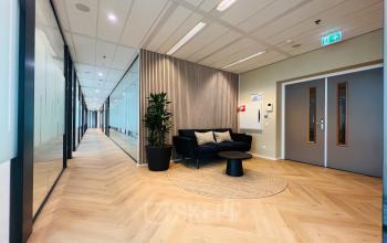 Lobby van het kantoorpand aan Vliegend Hertlaan 15 in Utrecht Zuid. Moderne inrichting met een zwarte bank, ronde tafel en planten. Ideaal voor bedrijven die kantoorruimte willen huren in een stijlvolle omgeving.