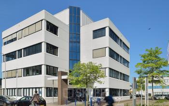 kantoorpand buitenzijde parkeerplaats auto's entree utrecht bomen fietser