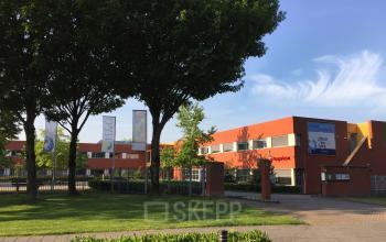 Kantoorpand op Kerkhofstraat 21, Valkenswaard, met modern ontwerp en groene omgeving. Kantoorruimte huren mogelijk in dit gebouw met oranje gevel en ruime parkeergelegenheid.