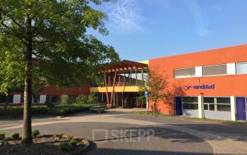 Kantoorpand op Kerkhofstraat 21, Valkenswaard met opvallende oranje gevel, boom voor het gebouw, en Randstad-logo op de gevel.