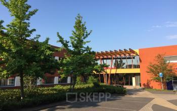 Exterieur van kantoorpand aan Kerkhofstraat 21 in Valkenswaard omgeven door bomen en parkeerplaatsen.