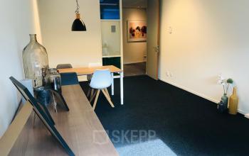 Kantoorruimte huren aan Kerkhofstraat 21 in Valkenswaard, lichte ruimte met houten meubels en decoratieve elementen, ideaal voor productief werk.