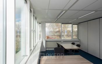 Lichte kantoorruimte in kantoorpand Vendelier 61 Veenendaal, met ramen langs de wand en eenvoudige meubelen, waaronder een vergadertafel met stoelen, ideaal voor huur als werkruimte.