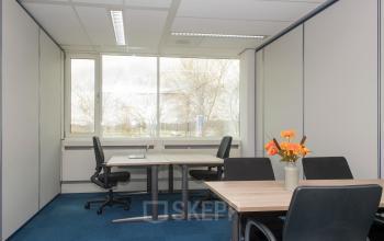 Moderne kantoorruimte met licht houten bureau, zwarte stoelen en een vaas met oranje bloemen, natuurlijk daglicht in Vendelier 61, Veenendaal