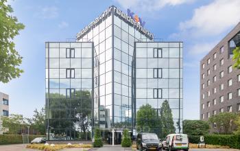 Modern kantoorpand Vendelier 61 in Veenendaal met spiegelende glasfaçade en ingangsgebied.