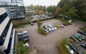 Exterieur van kantoorpand Vendelier 59 in Veenendaal met ruime parkeerplaats en groene omgeving, ideaal voor kantoorruimte huren.