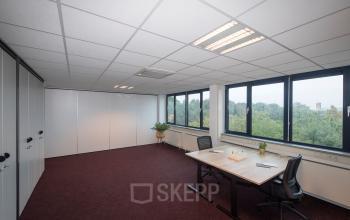 Lichte kantoorruimte met grote ramen en eenvoudige inrichting op de Vendelier 59 in Veenendaal. Twee bureaus met stoelen en enkele planten. Ideaal voor kantoorruimte huren.