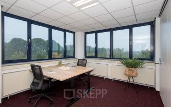 Kantoorruimte huren op Vendelier 59 in Veenendaal met twee bureaus, stoelen en een groene plant naast grote ramen met uitzicht.
