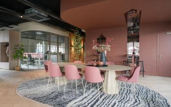 Vergaderruimte in Veghel op Doornhoek 3745, met moderne inrichting en ronde tafel omringd door roze stoelen.