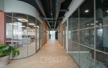 Een moderne kantoorruimte met glazen wanden en houten vloer in het kantoorpand op Doornhoek 3745, Veghel. Heldere werkplekken zijn zichtbaar door de ramen. Ideaal om kantoorruimte te huren voor groeiende bedrijven.