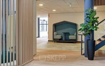 Moderne kantoorruimte op De Run 4312 in Veldhoven met comfortabele zitgelegenheid en een groene plant, ideaal om een kantoor te huren.