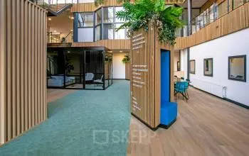 Interieur van modern kantoorpand op De Run 4312, Veldhoven, met kleurrijke muren, groen tapijt en een rustige zithoek waar je kantoorruimte kunt huren.