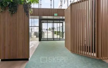 Moderne ingang van kantoorpand De Run 4312 in Veldhoven met ruime doorgang, natuurlijke lichtinval, en houtaccenten voor een stijlvolle uitstraling. Ideaal voor bedrijven die kantoorruimte willen huren.