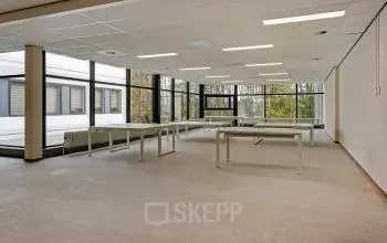 Lichte kantoorruimte huren bij De Run 4312 in Veldhoven, met grote ramen en uitzicht op bomen. Geschikt voor diverse kantooractiviteiten.
