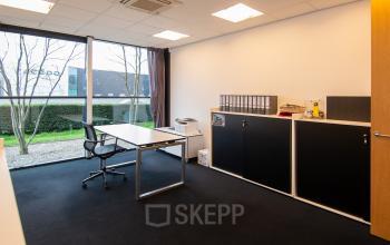 Kantoorruimte huren op Gildestraat 13, Velp met grote ramen, bureau en opslagkasten, gevestigd in een modern kantoorpand.