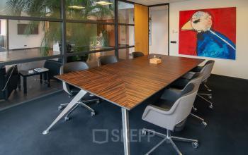 Stijlvolle vergaderruimte in kantoorpand op Gildestraat 13, Velp, met moderne stoelen rondom een lange houten tafel, perfect voor kantoorruimte huren.