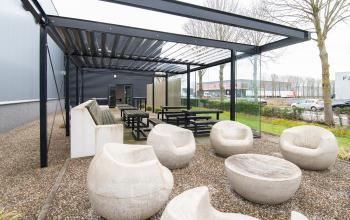 Kantoorpand met moderne buitenruimte op Gildestraat 13 in Velp, ideaal voor bedrijfspauzes of informele vergaderingen. Overdekte zitplaatsen en designstoelen bieden een stijlvolle plek voor ontspanning.