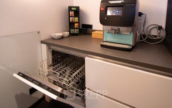 Koffiecorner in een kantoorpand op Gildestraat 13, Velp. Open vaatwasser en koffiemachine aanwezig, ideaal voor huurders die een kantoorruimte zoeken met voorzieningen.