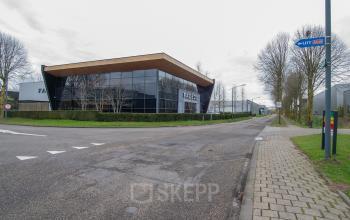 Modern kantoorpand op Gildestraat 13 in Velp, te huur, gekenmerkt door een strakke, glazen gevel en een rustige omgeving. Ideaal voor wie kantoorruimte zoekt.