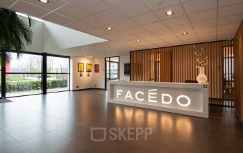 Modern ingerichte entree van een kantoorpand op Gildestraat 13 in Velp, met veel lichtinval, strakke vloeren en een opvallende balie. Ideale plek voor kantoorruimte huren.