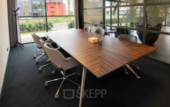 Vergaderruimte in een kantoorpand op de Gildestraat 13 in Velp met een stijlvolle houten tafel en comfortabele stoelen, ideaal voor kantoorruimte huren.