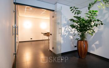 Moderne kantoorpand entree met glazen deur, planten en strakke afwerkingen op Gildestraat 13 in Velp, ideaal voor kantoorruimte huren.