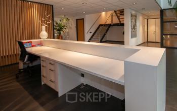 Receptie in kantoorpand op Gildestraat 13, Velp. Moderne balie met stoel en decoratie, ideaal voor bedrijven die kantoorruimte willen huren. Strakke afwerking en rustige sfeer. Perfect voor ontvangst van gasten.
