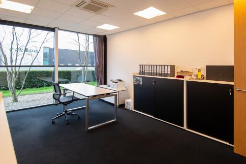 Kantoorruimte huren op Gildestraat 13, Velp met grote ramen, bureau en opslagkasten, gevestigd in een modern kantoorpand.