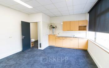 Kantoorruimte huren op Kaldenkerkerweg 28 in Venlo met een keukengedeelte, lichte muren, grijze vloerbedekking en grote ramen voor natuurlijk lichtinval.