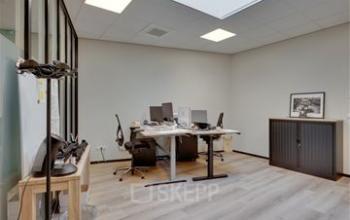 Moderne kantoorruimte met houten vloer, bureau met schermen en kasten op Noorderpoort 43, Venlo, geschikt voor diverse zakelijke activiteiten.