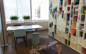 Moderne kantoorruimte op Kaldenkerkerweg 20 in Venlo met grote boekenwand, diverse stoelen en veel daglicht. Ideaal voor wie kantoorruimte wil huren voor creatieve brainstormsessies of als gezellige werkplek.