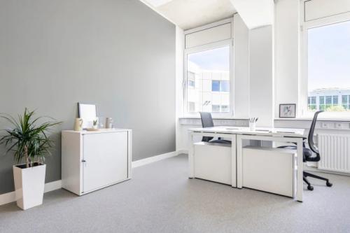 Een lichte kantoorruimte in Venlo met modern meubilair en grote ramen die daglicht binnenlaten, ideaal om te huren voor productieve werkuren.