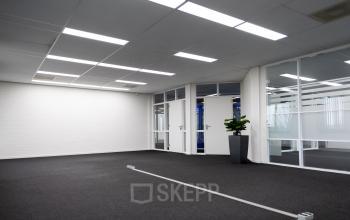 Kantoorruimte huren aan de Parlevinkerweg 1 in Venlo, met moderne glazen wanden, tapijtvloer en een fraaie plantenbak in de hoek.