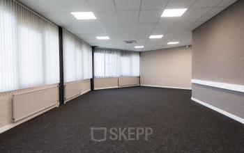 Ongemeubileerde kantoorruimte te huur op Parlevinkerweg 1 in Venlo, met lichte muren, grote ramen en grijze vloerbedekking.