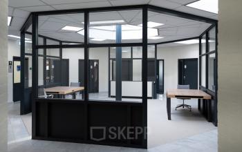 Ruime kantoorpand op Parlevinkerweg 1 in Venlo met moderne glazen wanden en enkele bureaus.