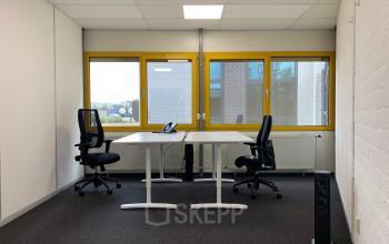 Kantoorruimte huren op Parlevinkerweg 1, Venlo: lichte ruimte met twee bureaus, bureaustoelen en grote ramen.