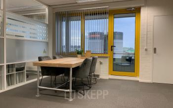 Kantoorruimte op Parlevinkerweg 1 in Venlo met vergadertafel, stoelen en grote ramen.