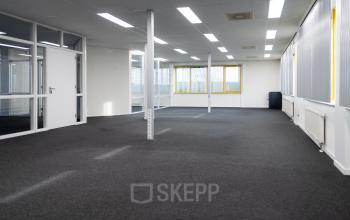 Ongebruikt kantoor op Parlevinkerweg 1, Venlo met grote ramen, tapijt en witte muren.
