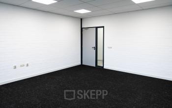 Leeg kantoorpand te huur op Parlevinkerweg 1, Venlo met neutrale muren en donkere vloerbedekking.