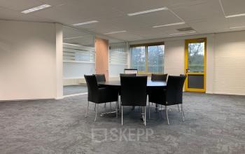 Vergaderruimte in het kantoorpand op Parlevinkerweg 1, Venlo, voorzien van een tafel met stoelen en veel natuurlijk licht.