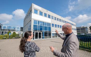 Het kantoorpand op Witboom 1 in Vianen Utr, een modern gebouw met grote glazen gevel, geschiktheid voor kantoorruimte huren. Twee personen zijn in gesprek over de mogelijkheden.