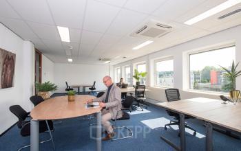 Kantoorruimte huren bij Witboom 1 in Vianen Utr. Twee mannen zittend aan moderne bureaus, verdiept in zakelijke activiteiten. Ruime, lichte kantooromgeving met grote ramen en ergonomische stoelen.