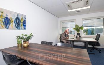 Kantoorruimte huren in Vianen Utr op Witboom 1 met moderne werkplekken, veel natuurlijk licht en een persoon aan het werk achter een bureau met laptop.