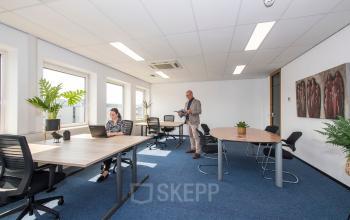 Binnen in het kantoorpand op Witboom 1, Vianen Utr, zie je lichte werkplekken met tafels en stoelen. Twee mensen zijn bezig met zakelijke activiteiten. Ideaal voor kantoorruimte huren.