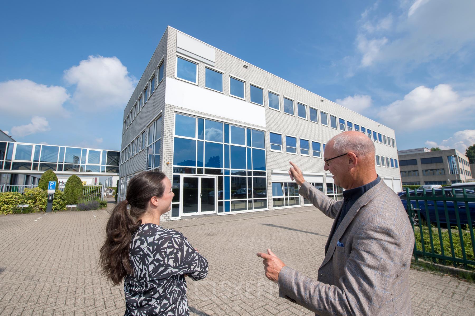 Het kantoorpand op Witboom 1 in Vianen Utr, een modern gebouw met grote glazen gevel, geschiktheid voor kantoorruimte huren. Twee personen zijn in gesprek over de mogelijkheden.