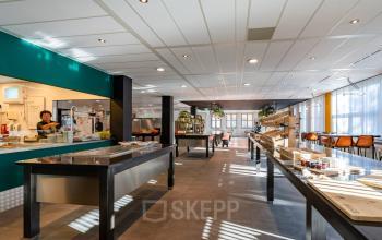 Gezellige pantry in kantoorpand aan Lange Dreef 17, Vianen Utr, met moderne inrichting en personeelslid dat druk in de keuken bezig is.