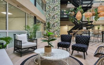 Sfeervolle ingerichte lounge in kantoorpand op Havenweg 24, Vianen Utr. Ideaal voor wie kantoorruimte wil huren. Gezellige zithoek met planten en unieke lampen in open ruimte.
