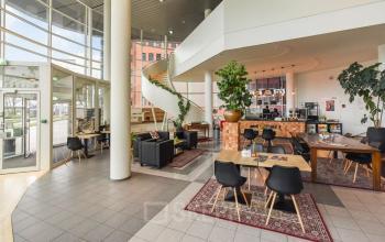 Moderne en lichte kantoorruimte met open vloerplan en verschillende zitgedeeltes op Regulusweg 11, Voorburg. Ideale kantoorpand voor huren met ontspannende sfeer en grote ramen.